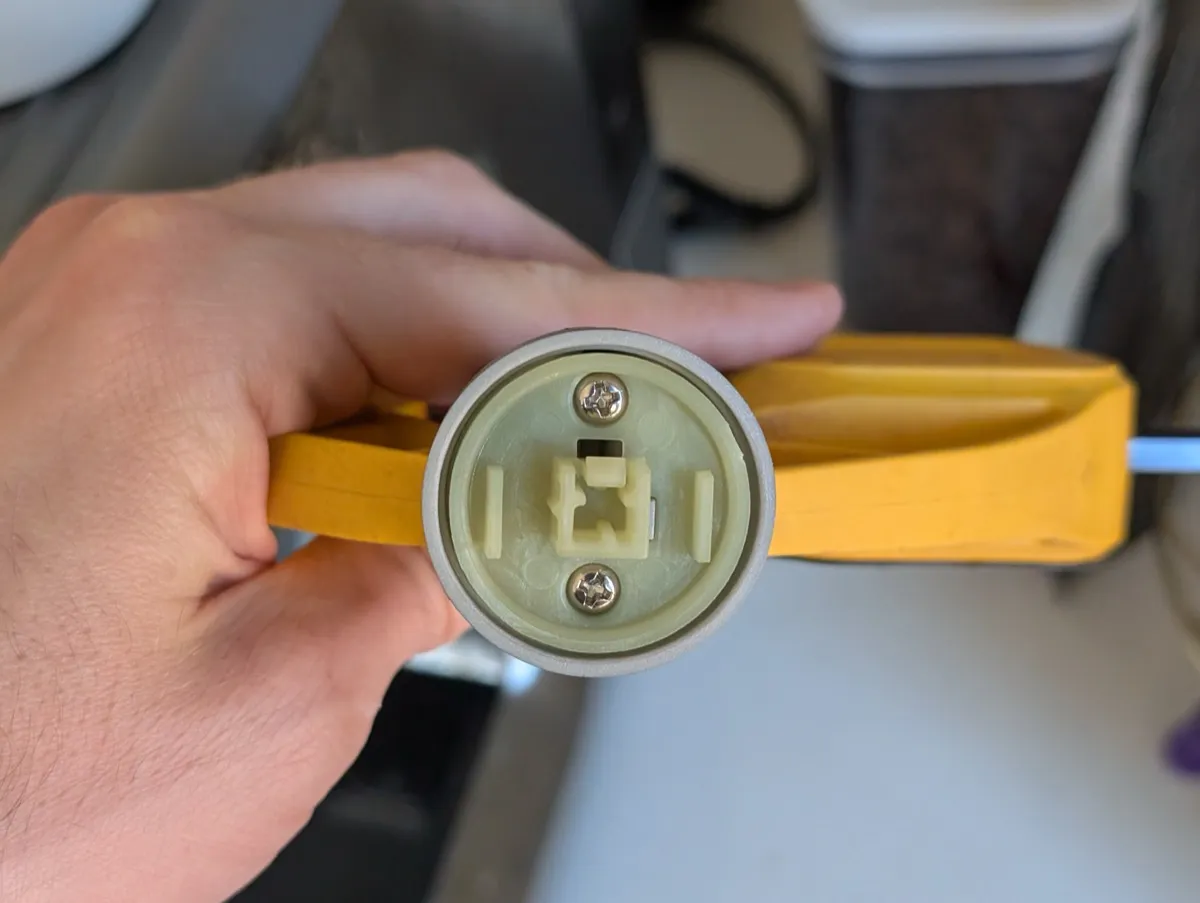 The inside of the removed knob, showing the square plastic coupling mechanism and mounting screws